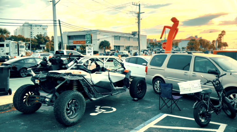 Cars, motorcycles, and buggies parked waiting for the Artemis launch with Wells Fargo building to the left side.