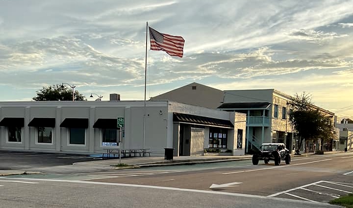 An image of an event center with an American flag waving in the air and a buggie coming towwards a stop sign.