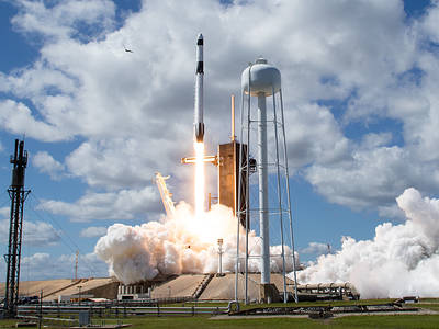 A rocket is lifting off with the water tower next to it.