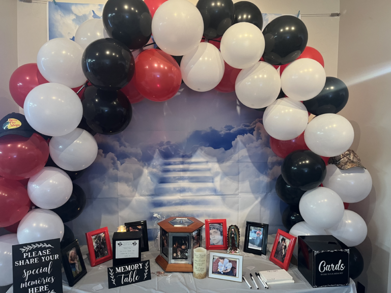 Memory table with balloon arch and pictures.